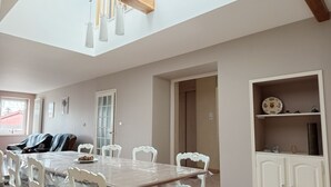 A dining area with a large table, white chairs, a wooden ceiling, and a white cabinet with shelves. - Le Charme Des Cerisiers - 3-star family B&B with private spa and garden.  (Bouvigny-Boyeffles)