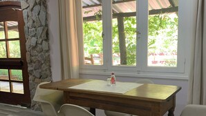 A dining area with a stone wall, a wooden table, and white chairs.
