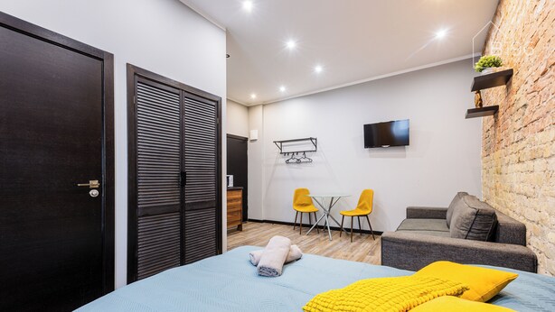 A bedroom with a bed, a TV, a small table, and a sofa. - ApartHotel Riga Self Registration & Check-in (Riga)