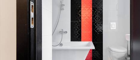 Baño con bañera blanca, inodoro y ducha.
