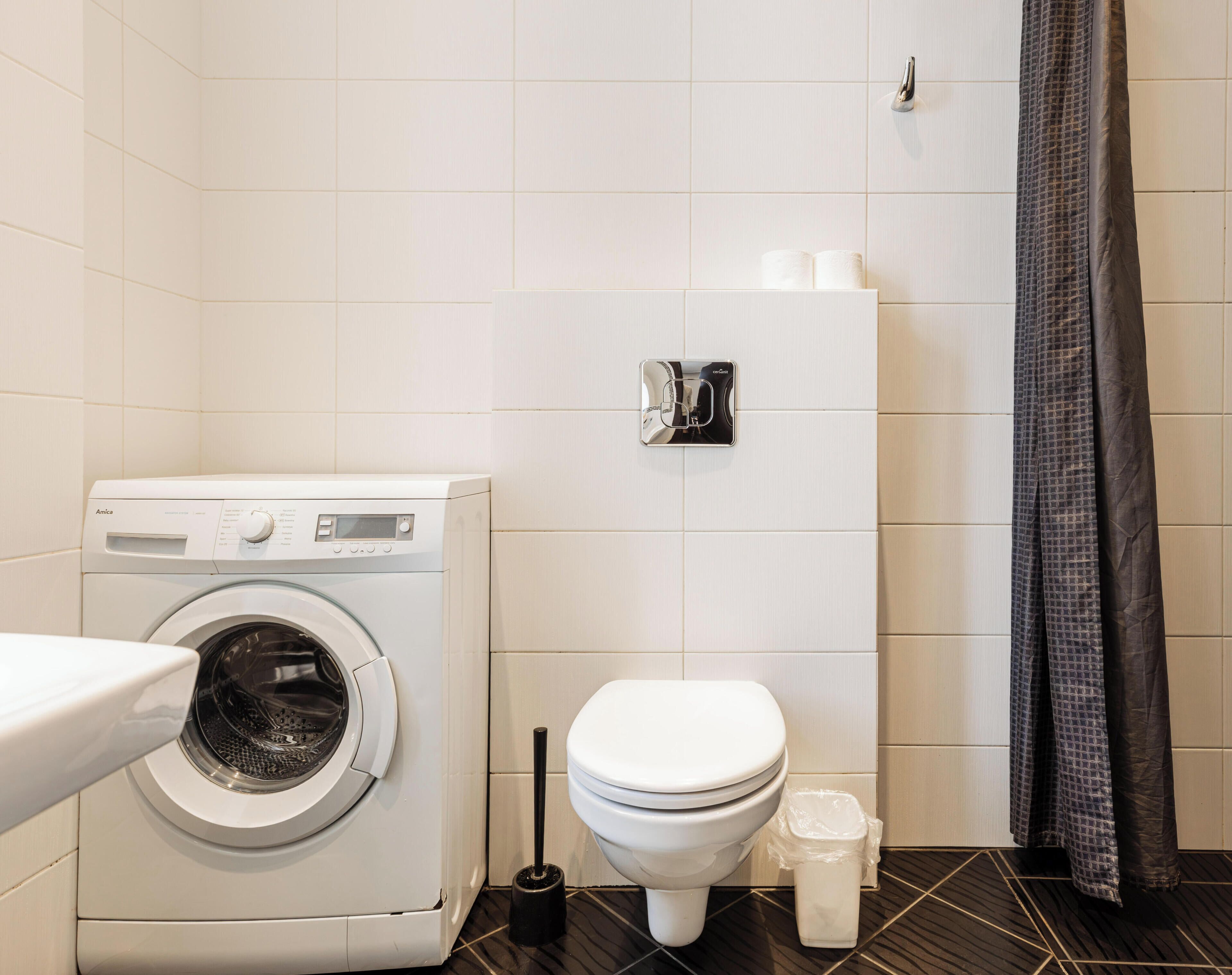 Ein kleines Badezimmer mit Waschmaschine, Toilette und Handtuchhalter.