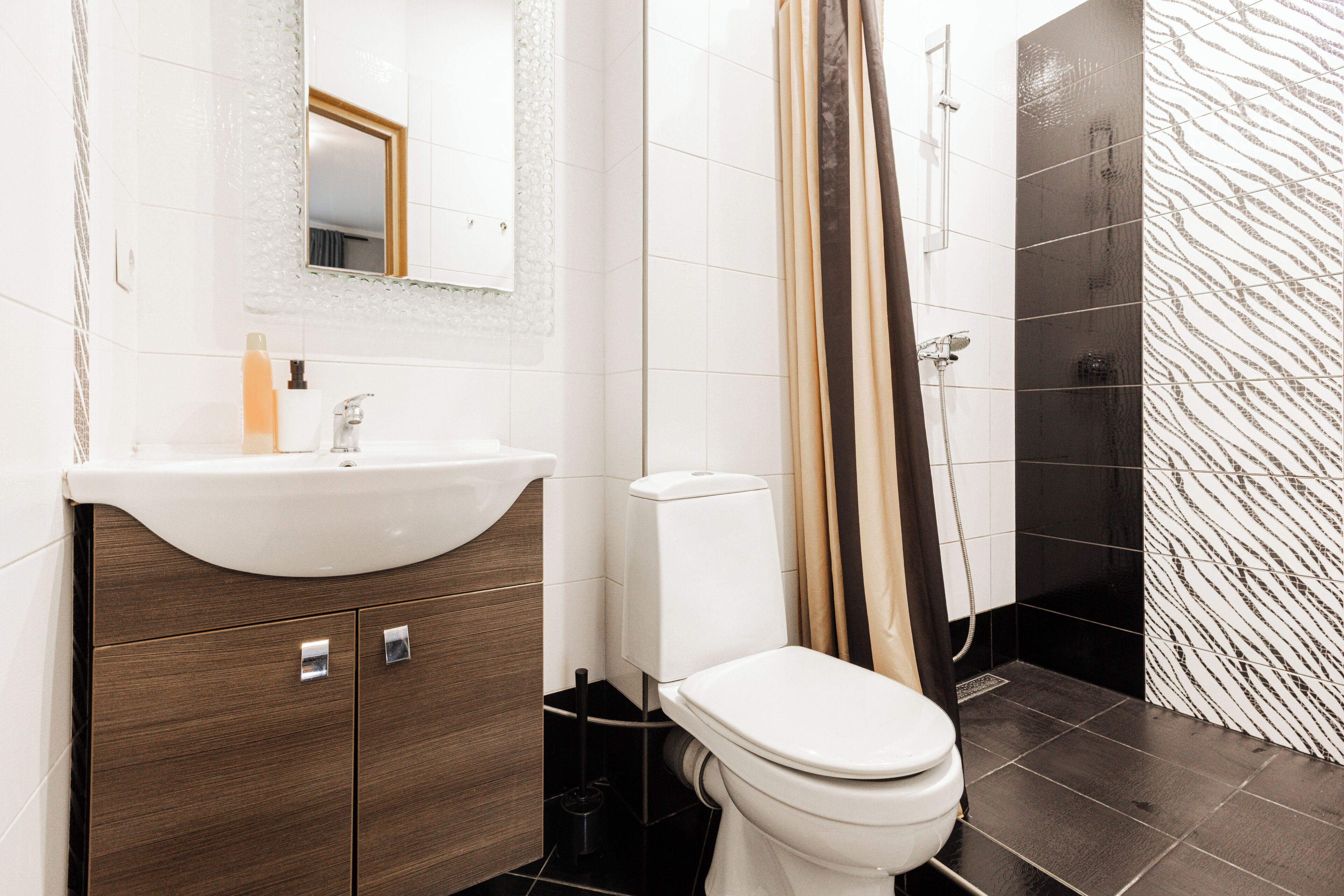 Et moderne badeværelse med vask, toilet, bruser og spejl.