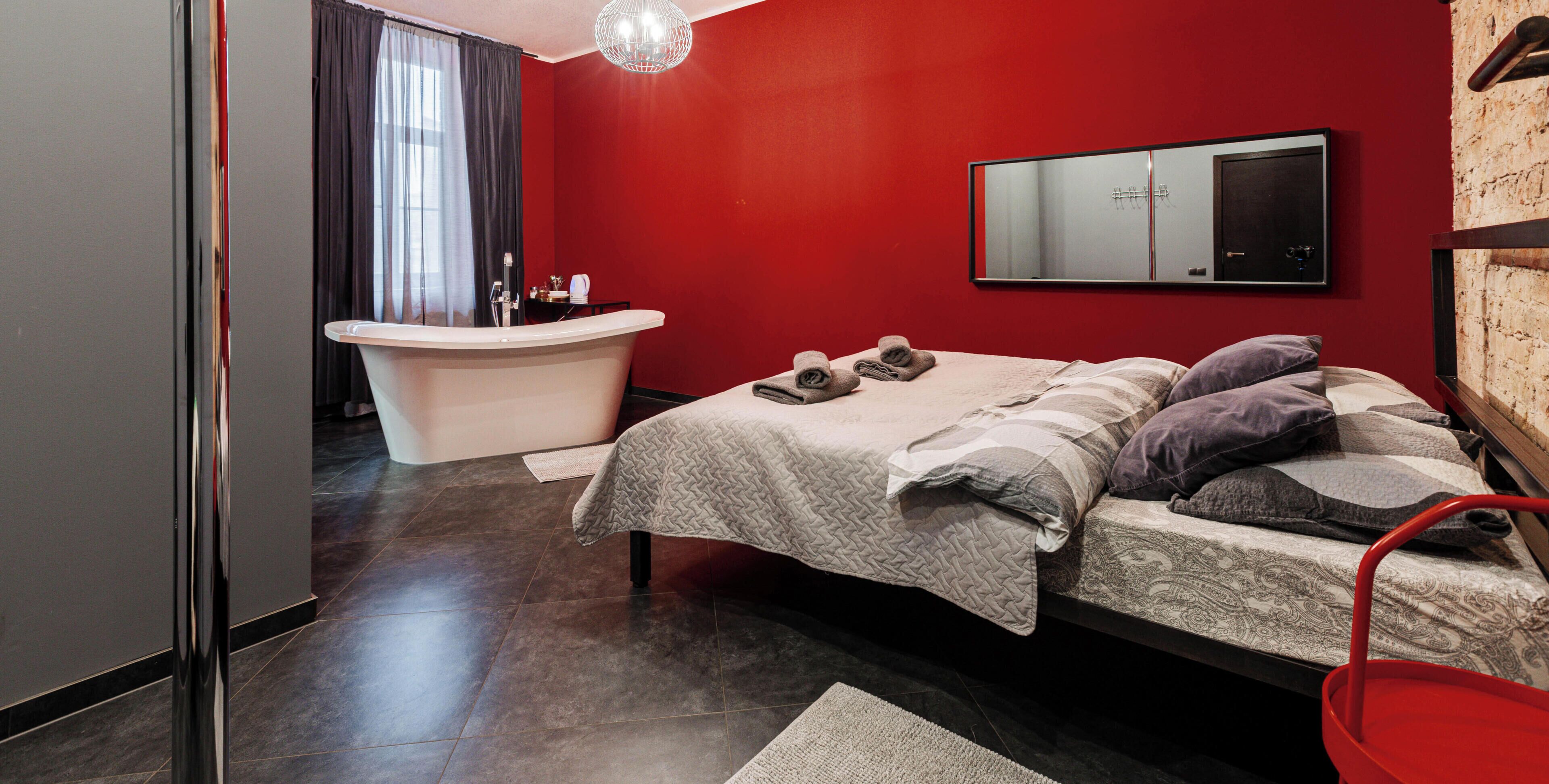 Un dormitorio moderno con una cama grande, una bañera integrada y un espejo en la pared.