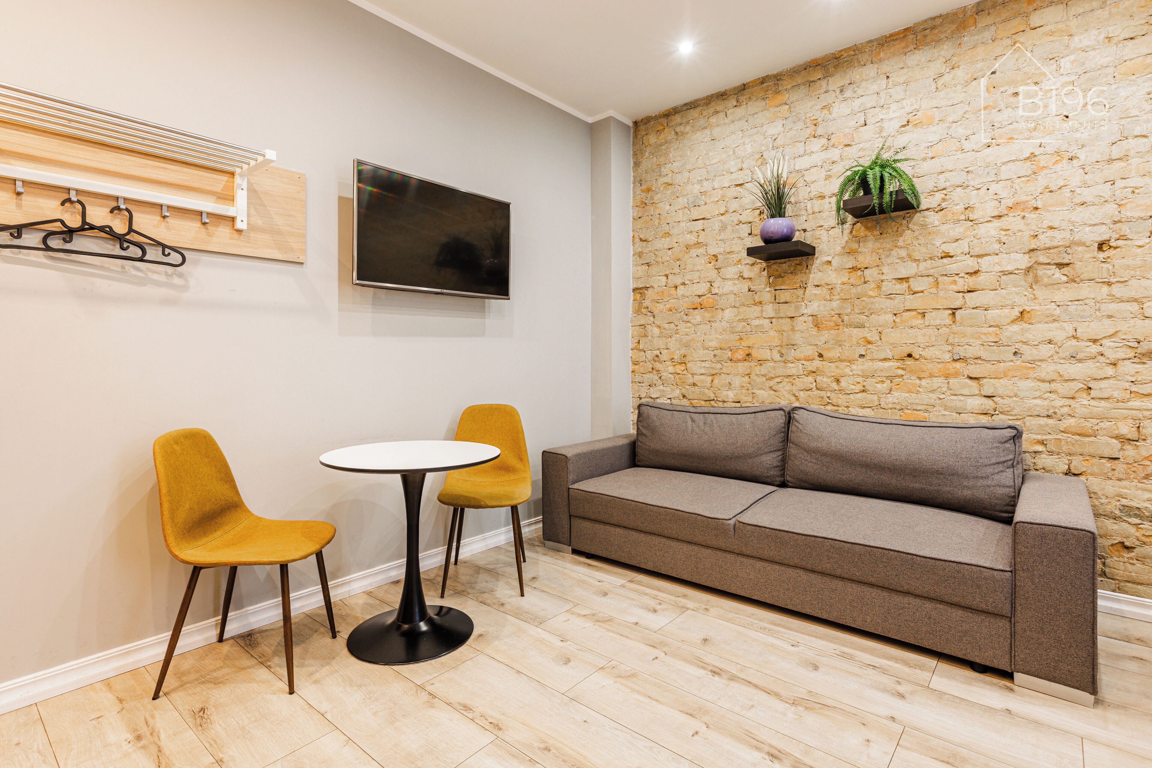 A room with a stone wall, a sofa, two chairs, a small table, and a mounted TV.