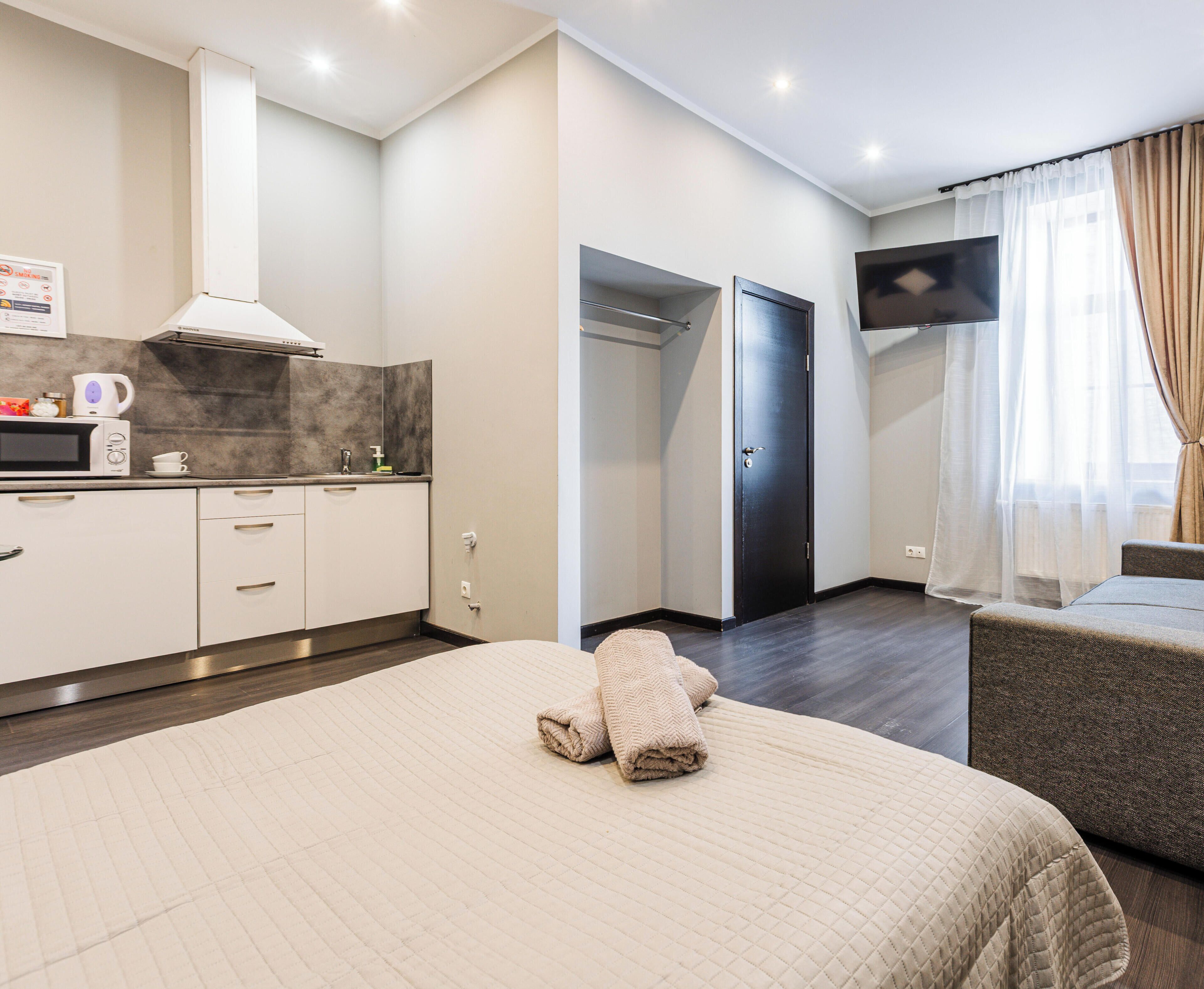 Una habitación de hotel con cama, televisor, kitchenette y baño.