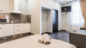 Una habitación de hotel con cama, televisor, kitchenette y baño.