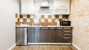A modern kitchen with a refrigerator, microwave, and a brick wall. - ApartHotel Riga Self Registration & Check-in (Riga)