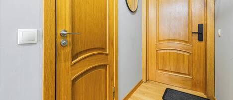 A wooden door with a handle and a keyhole, a doormat, and a light switch on the wall.