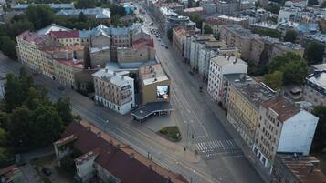 Luchtbeeld van een stadsgezicht met een mix van oudere en moderne gebouwen, een brede straat en een tramlijn.