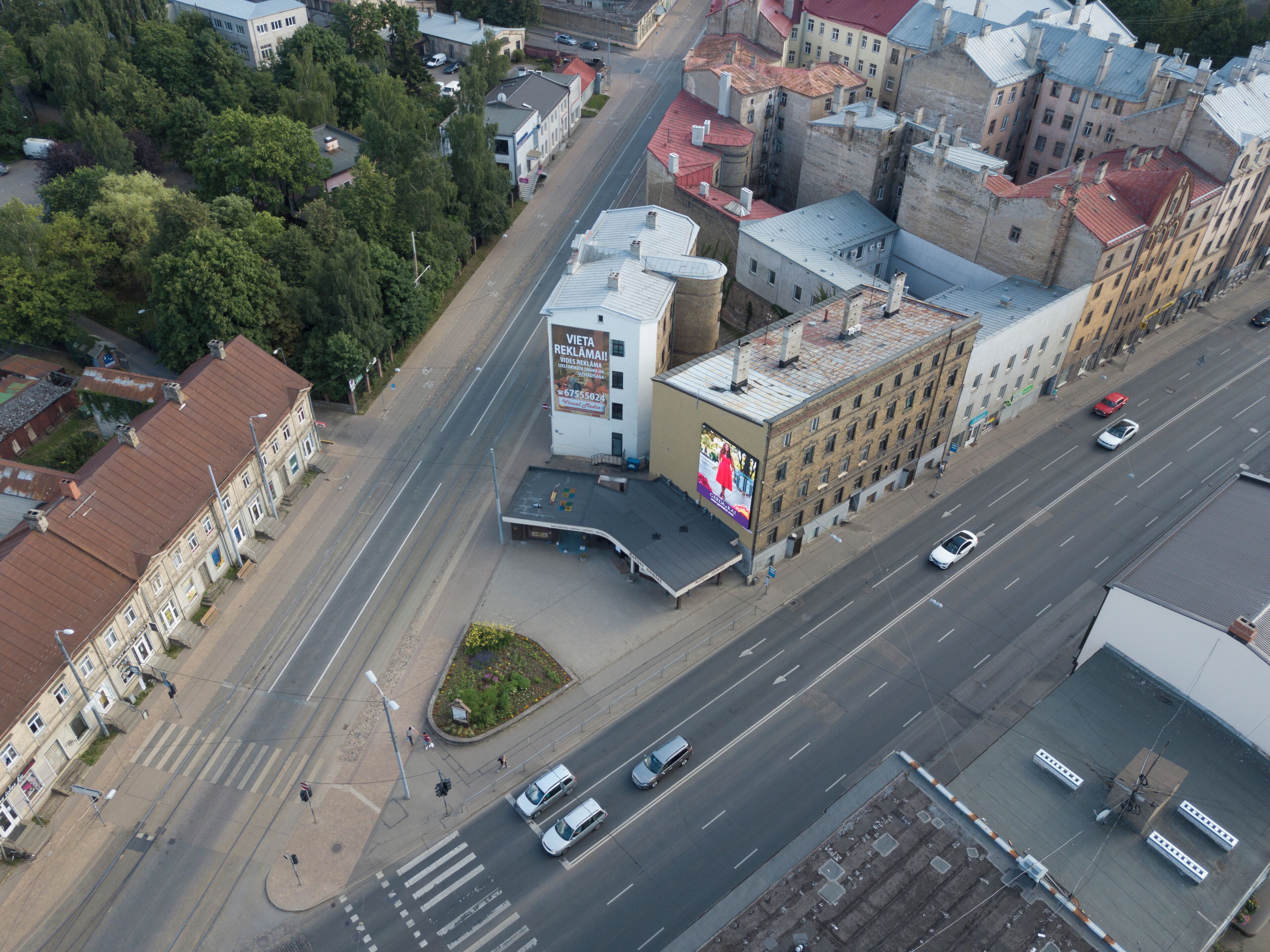 An aerial view of a city intersection with buildings, roads, and a billboard.