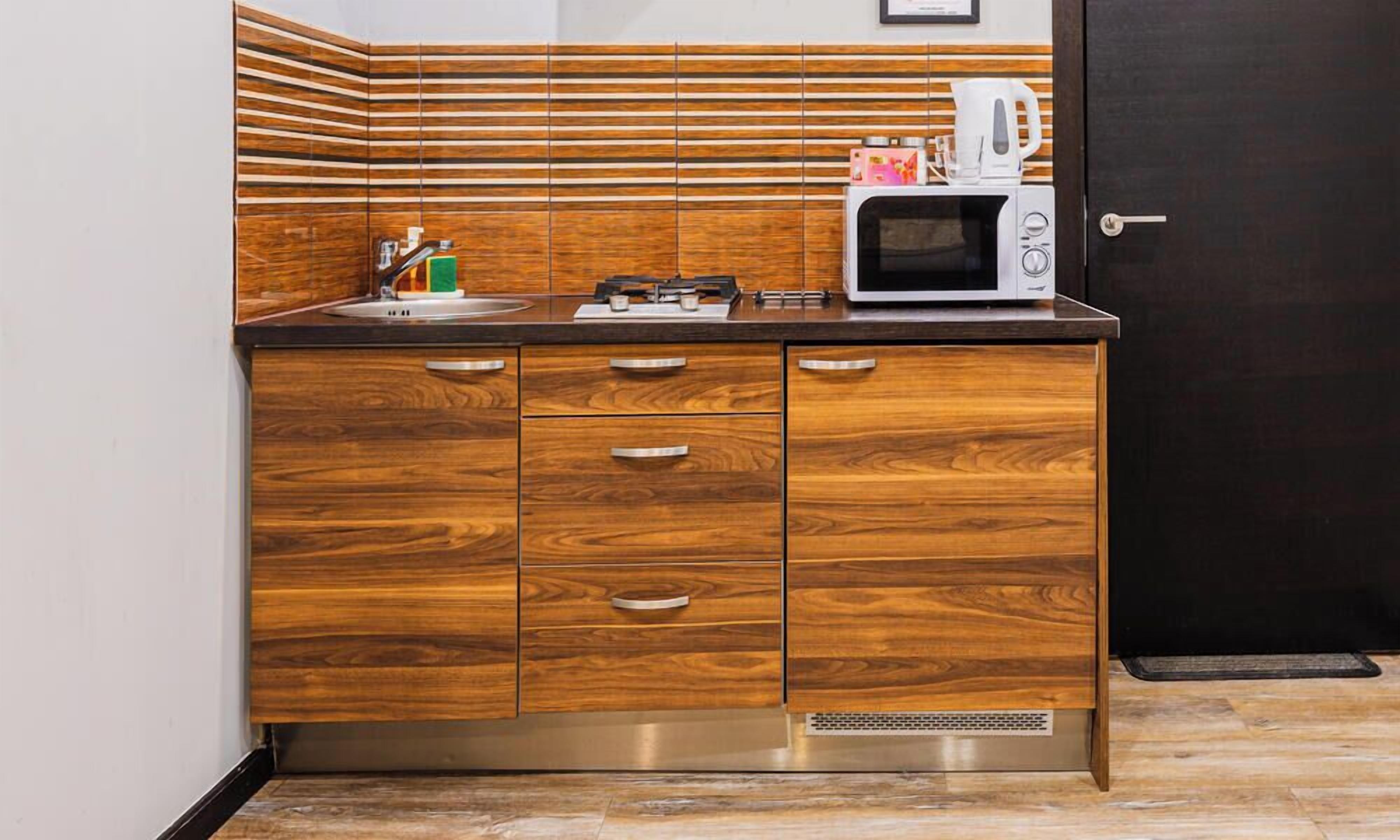A kitchen with a wooden cabinet, a microwave, and a coffee maker.