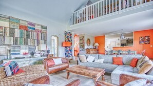 A spacious living room with a high ceiling, a staircase, and a view of the kitchen. - La Rocherie - Charmante maison avec piscine privée (Carnac)