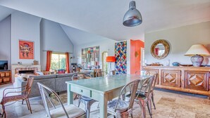 A spacious living area with a dining table, chairs, a sofa, and a fireplace. - La Rocherie - Charmante maison avec piscine privée (Carnac)