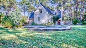 A two-story house with a sloped roof, surrounded by a well-maintained lawn and tall pine trees. - La Rocherie - Charmante maison avec piscine privée (Carnac)