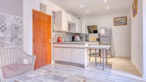 Una cocina moderna con armarios blancos, una puerta de madera y un comedor con mesa y sillas.