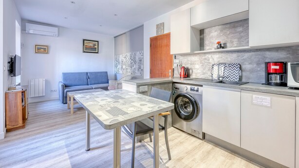 Una cocina moderna con lavadora, un comedor con mesa y sillas, y una sala de estar con sofá.