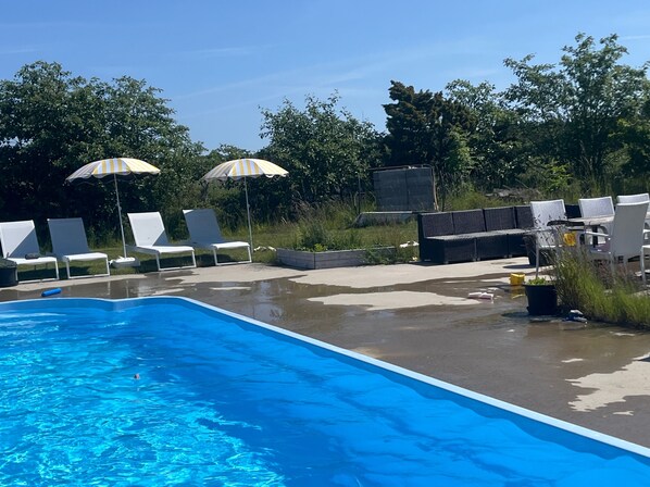 A swimming pool with lounge chairs and umbrellas.