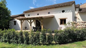 A white building with a tiled roof and a covered patio area. - Les Sechoirs - Gite La Riviera (Clairac)
