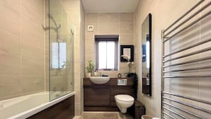 Une salle de bain moderne avec une douche à l’italienne en verre, une baignoire sur pieds, un meuble-lavabo en bois et des toilettes.