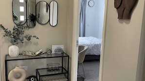 Une chambre à coucher avec un lit, une table de chevet dotée d’un miroir, une sculpture d’éléphant fixée au mur, et une porte donnant sur une autre pièce.