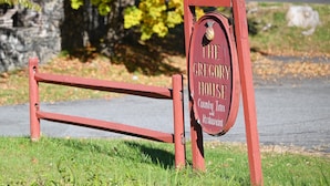 A wooden sign for The Gregory House, County Inn and Restaurant, with a rustic design and a natural backdrop.