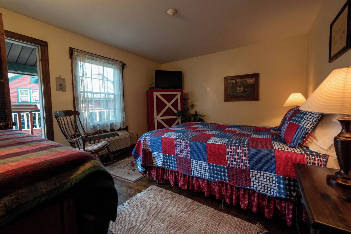 A bedroom with a bed, a chair, a lamp, and a window.