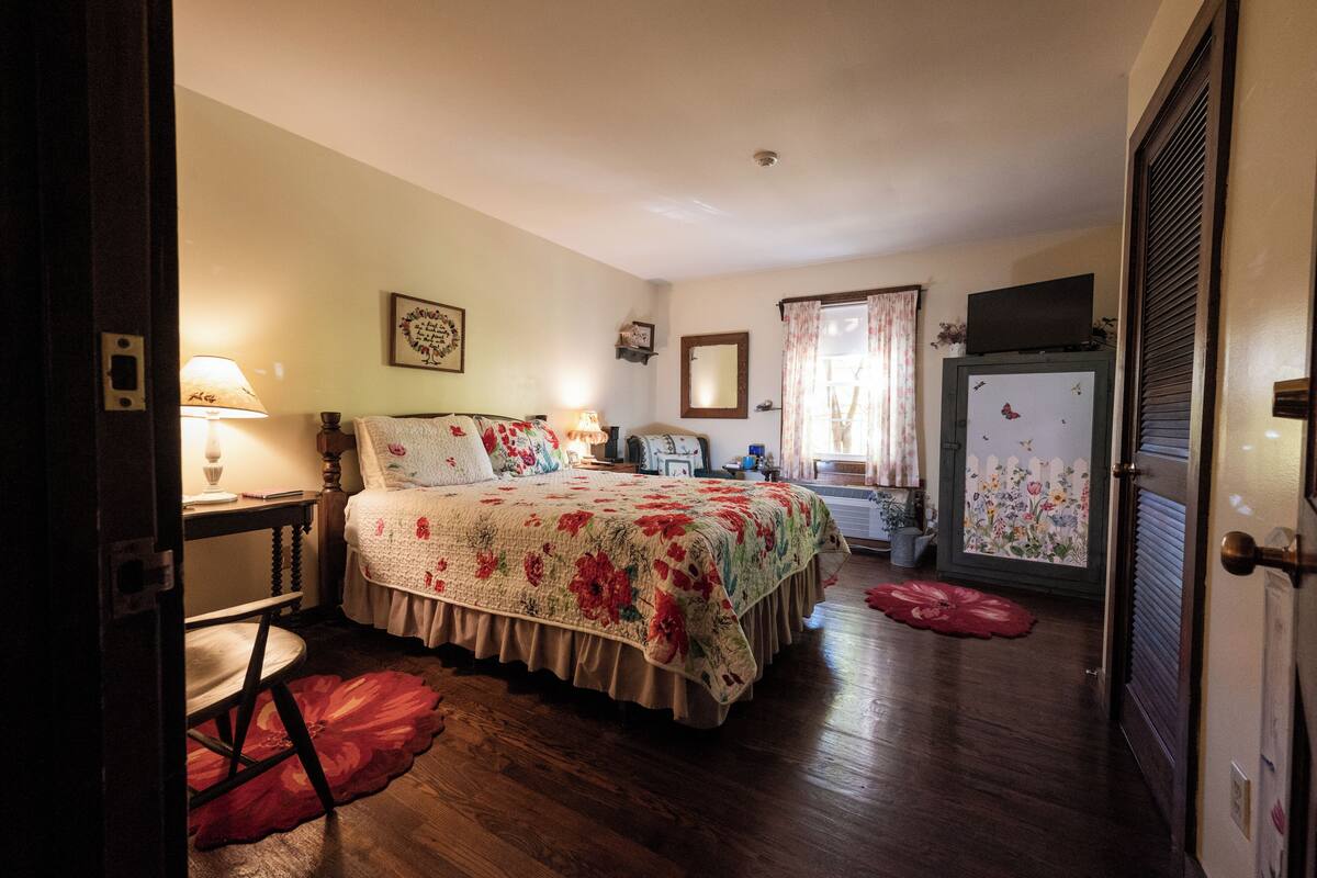 A bedroom with a bed, a dresser, a mirror, a television, and a door.