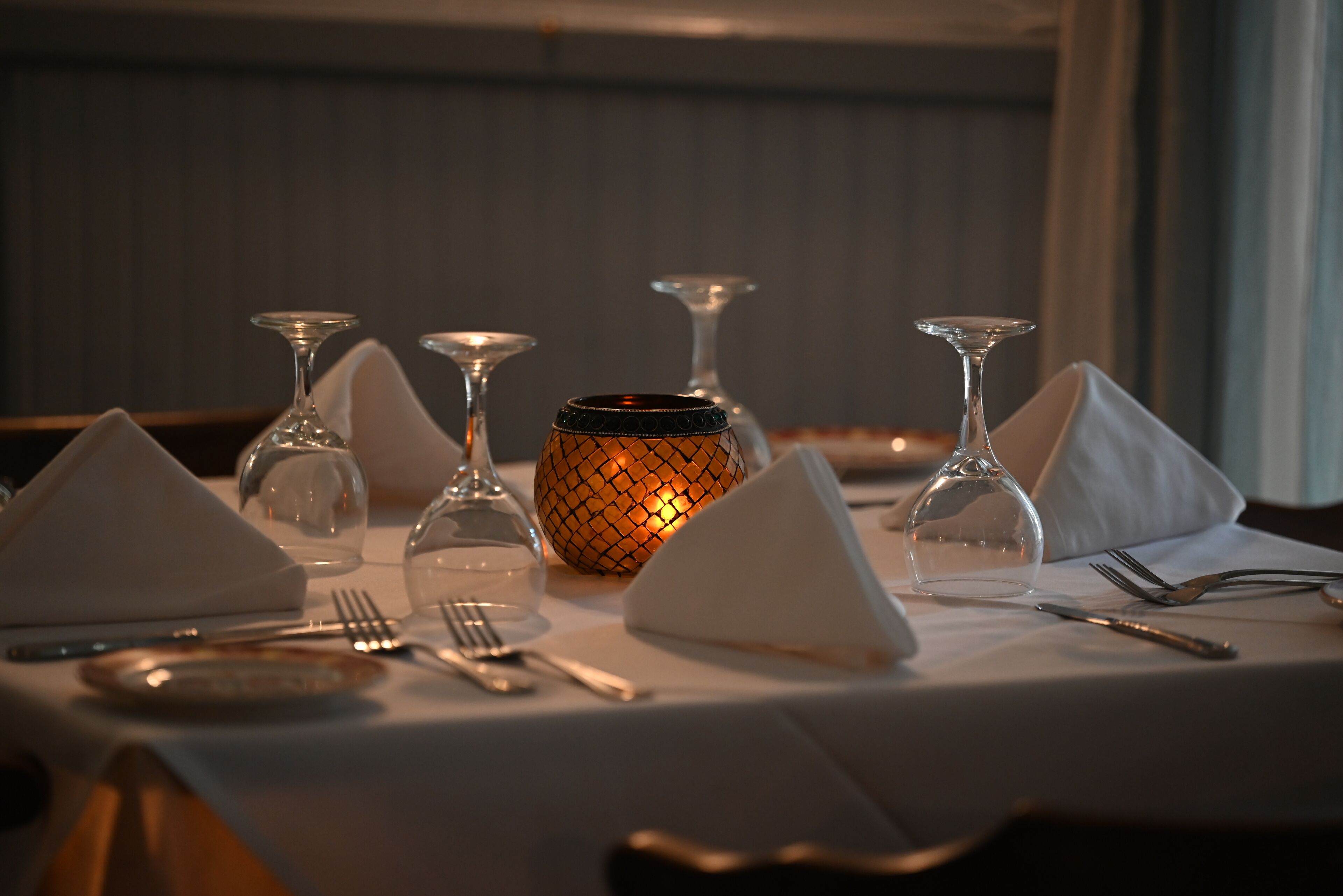 A table set for dining with wine glasses, a candle, and cutlery.
