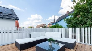 A wooden deck with a sectional sofa and a glass coffee table.