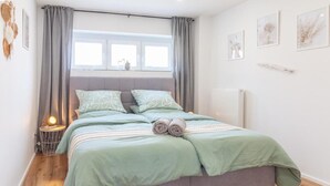 A bedroom with a bed, curtains, a bedside lamp, and wall art.