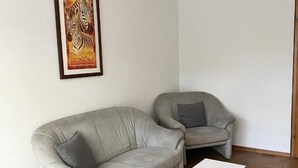 Een woonkamer met een grijze bank, een witte salontafel en een lijstwerk kunstwerk aan de muur.