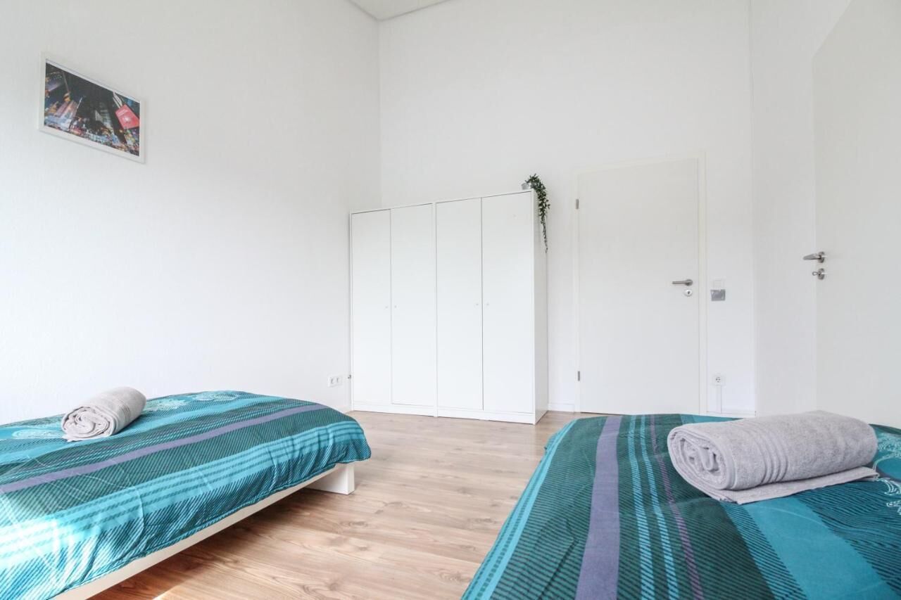 Una habitación con dos camas, un armario blanco y una puerta decorada con una planta.