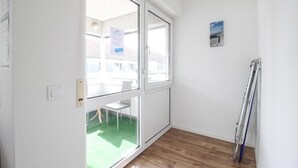 A room with a large sliding glass door leading to a balcony, a small white chair, and a pair of skis leaning against the wall. - nJoy! Sunny Apartment Göppingen | Balcony & Parking (Göppingen)