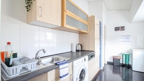 A modern kitchen with a dishwasher, sink, and a large wooden cabinet above the counter. - nJoy! Sunny Apartment Göppingen | Balcony & Parking (Göppingen)