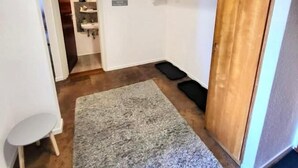 Ein Flur mit grauem Teppich, Holzschränken und einer weißen Wand mit einem hängenden Schild.