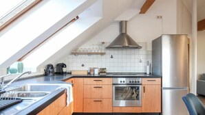 Una cocina moderna con tragaluz, electrodomésticos de acero inoxidable, armarios de madera y salpicadero de azulejos.