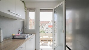 Eine moderne Küche mit Holzarbeitsplatte, eingebautem Spülbecken und Blick auf den Balkon.
