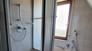 Een badkamer met een douche, toilet en wastafel.