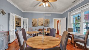 A dining area with a round wooden table, gray upholstered chairs, and a ceiling fan.
