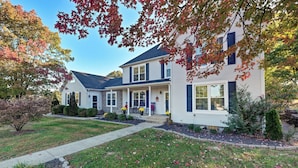 A two-story house with a front porch, a driveway, and a well-maintained lawn.