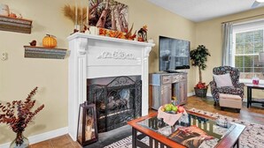 A living room with a fireplace, a dining area, and a large window.