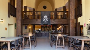 A spacious dining area with high wooden ceilings and a central bar. Tables and chairs are arranged for dining. - Magic Pirates Island Resort (Benidorm)