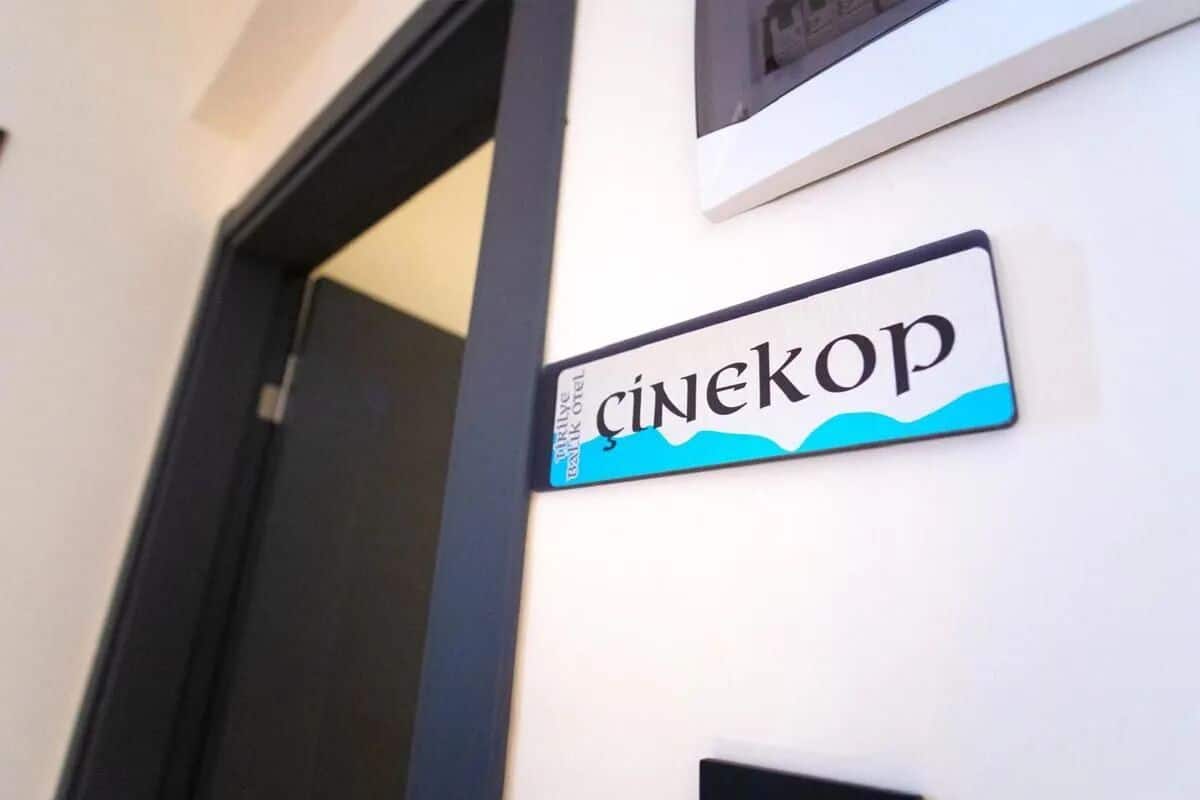 Una señal con el nombre 'Cinekop' sobre una pared blanca.