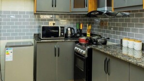 Une cuisine compacte avec des meubles gris, un four à micro-ondes, une cuisinière et un petit réfrigérateur.