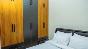 Une chambre d’hôtel avec un lit, une armoire à deux portes et une table de chevet.