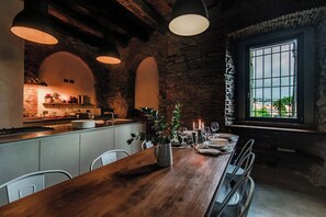 A rustic kitchen with a wooden table set for dining, stone walls, and a large window with a view. - Stone House (Alzate Brianza)