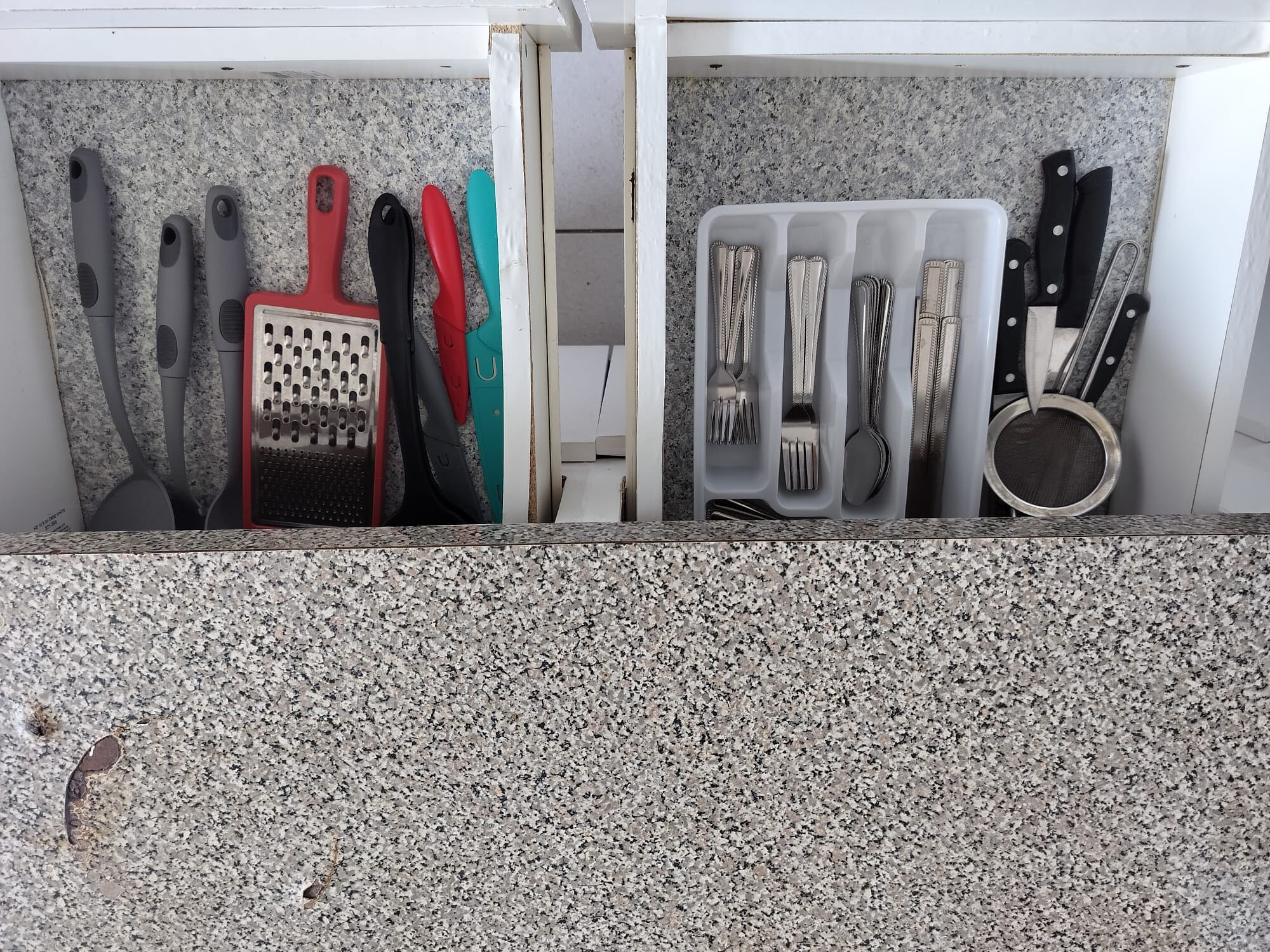 Een aanrecht met verschillende keukengerei en apparaten, waaronder een rasp, messen en een keukenmachine.