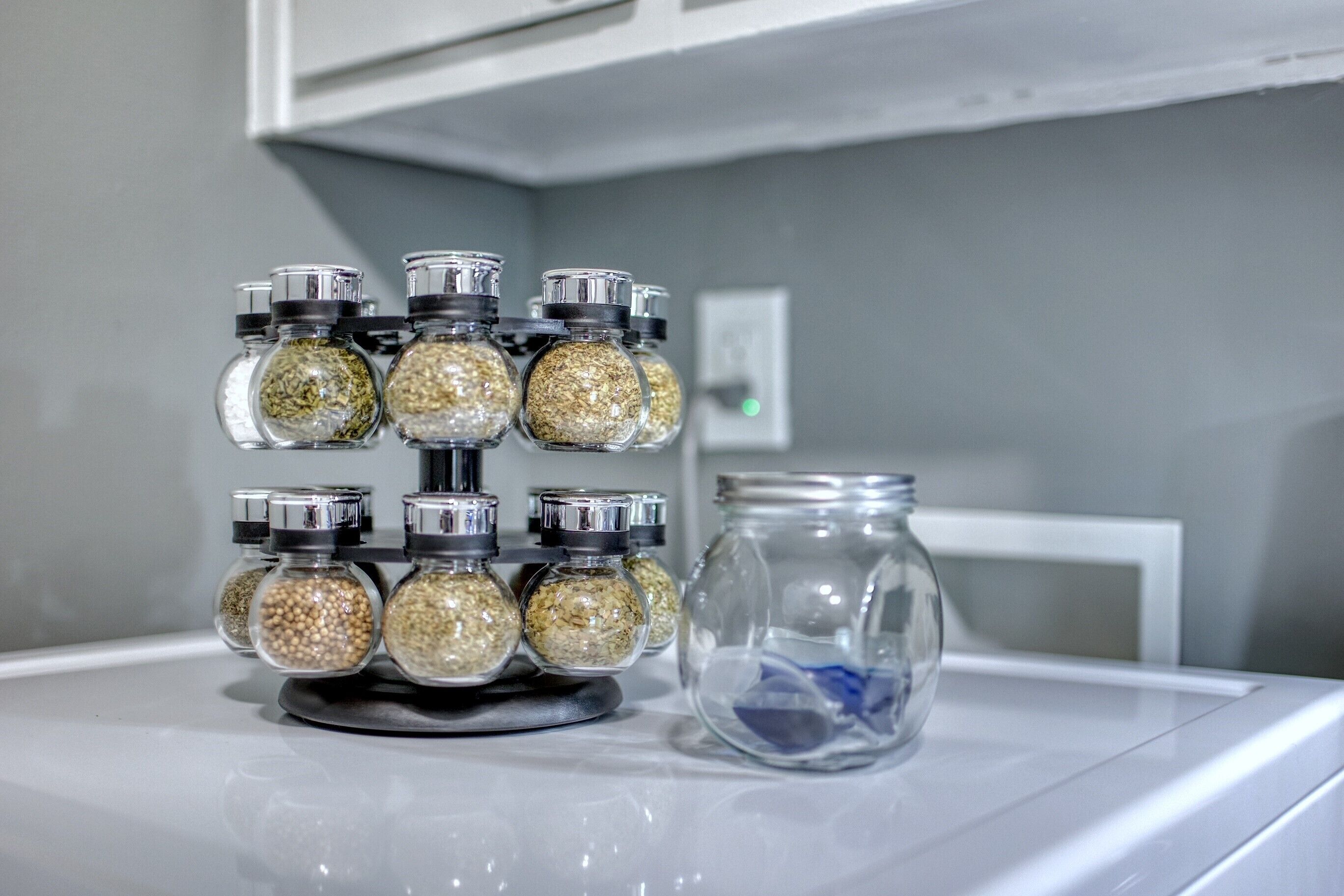 A kitchen with a spice rack holding glass jars filled with various spices.