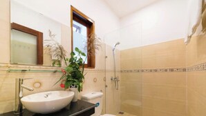 A bathroom with a large white sink, a toilet, and a shower.