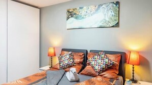 A hotel room with a bed, two nightstands, a wall-mounted painting, and two lamps. - Close to BER/Adlershof airport in a quiet location; freeway transportation; (Schönefeld)